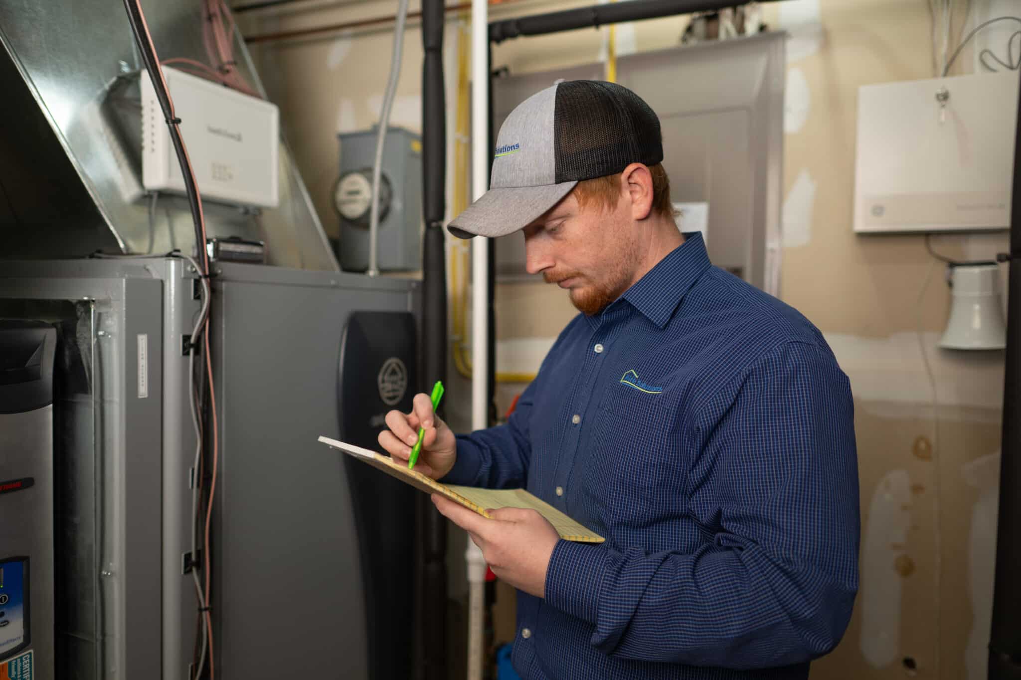 Aire Solutions technician conducting a whole-home humidity assessment beside an HVAC system.